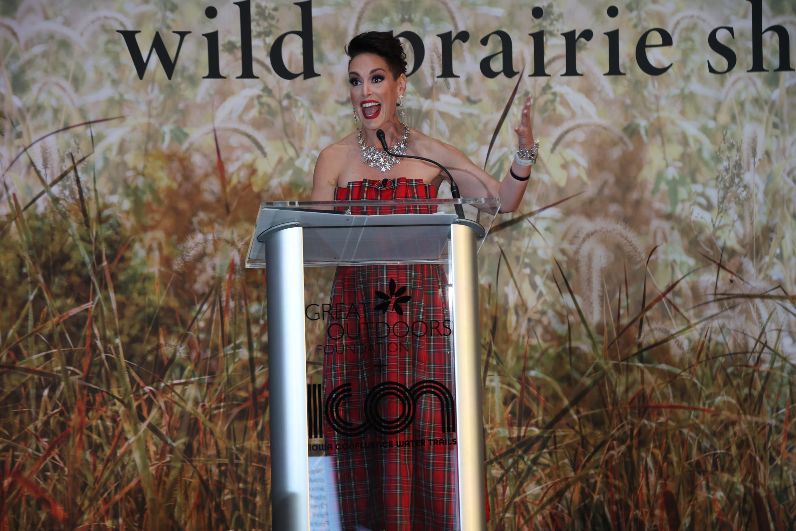 A woman speaking in to the microphone with a very big smile