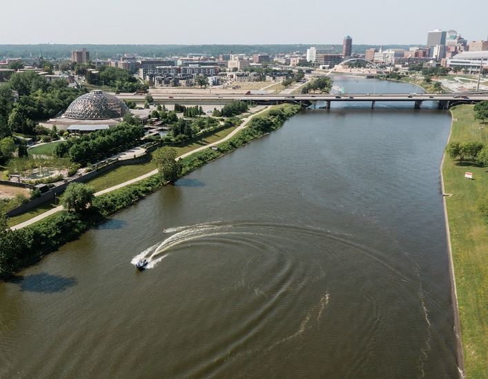 A boat creating a large wake in the Des Moines River along downtown Des Moines