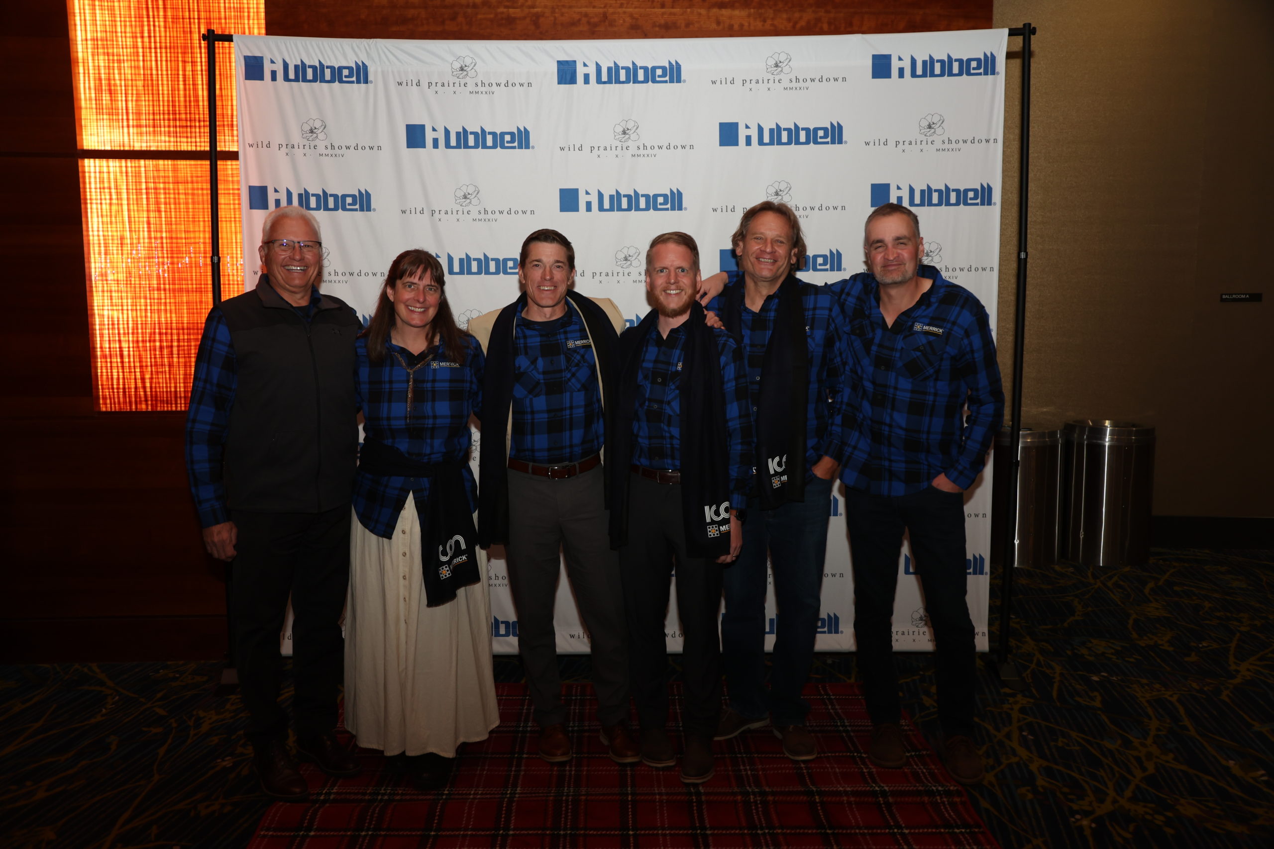 A group in matching shirts standing in front of a Hubbel backdrop