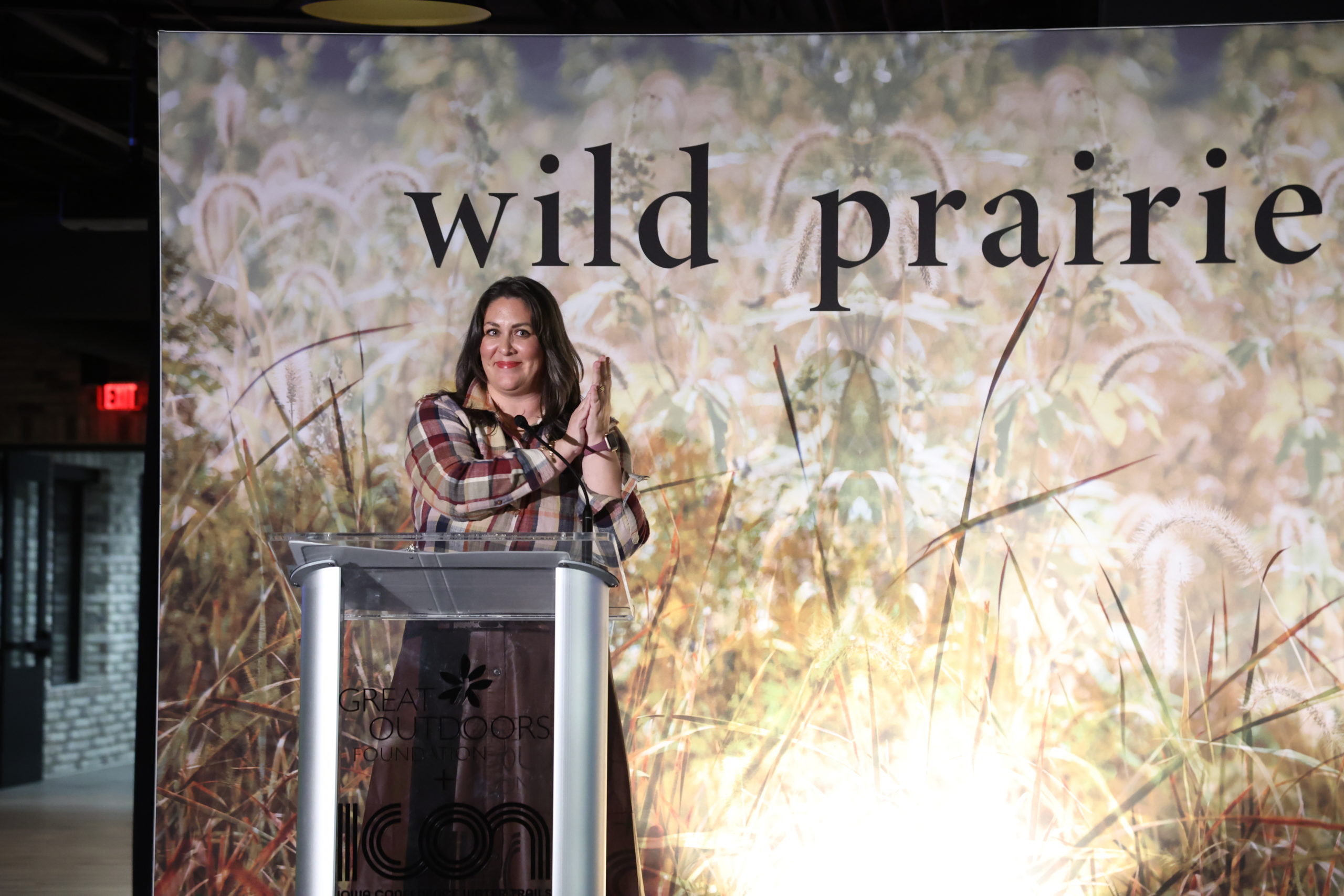 A presenter standing at the microphone and clapping
