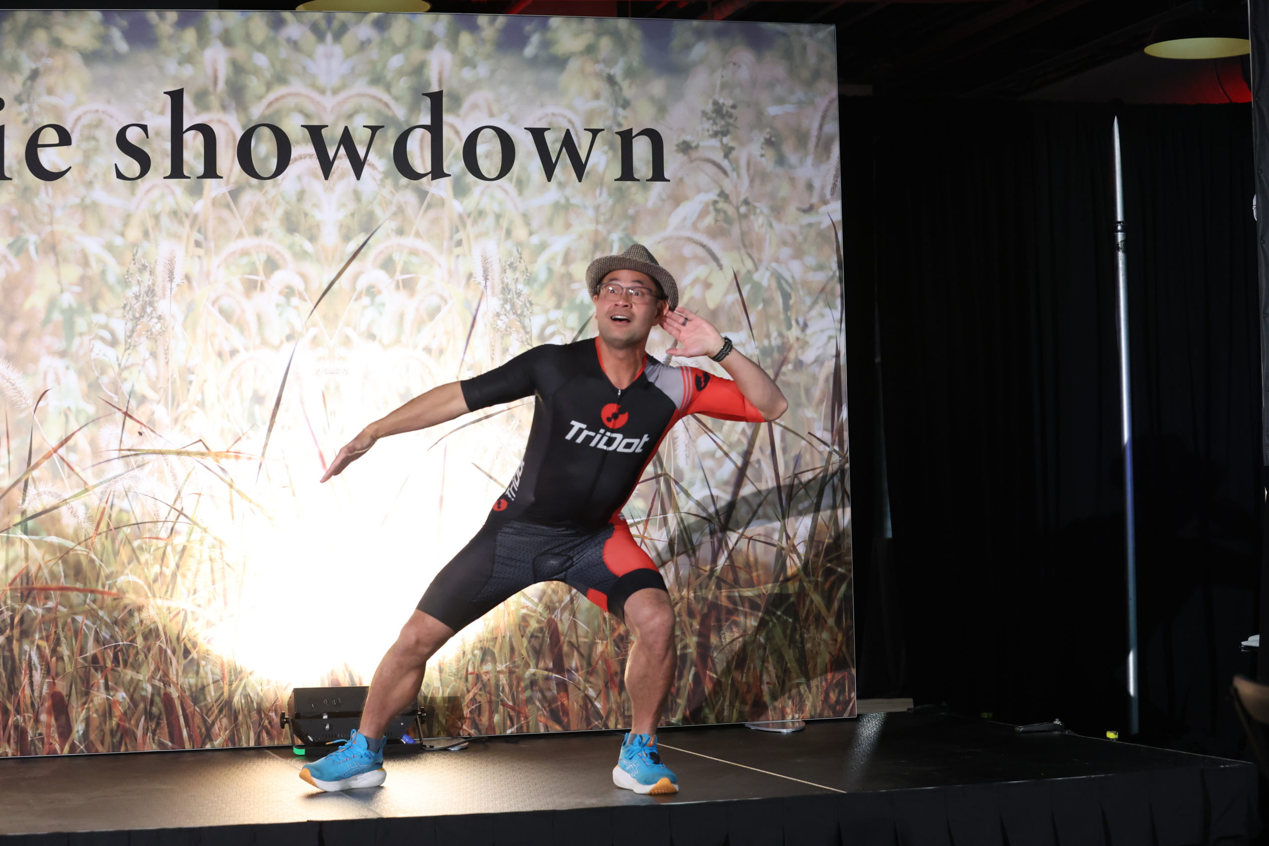 A man in a wetsuit hyping up the crowd by putting his hand to his ear encourage cheers