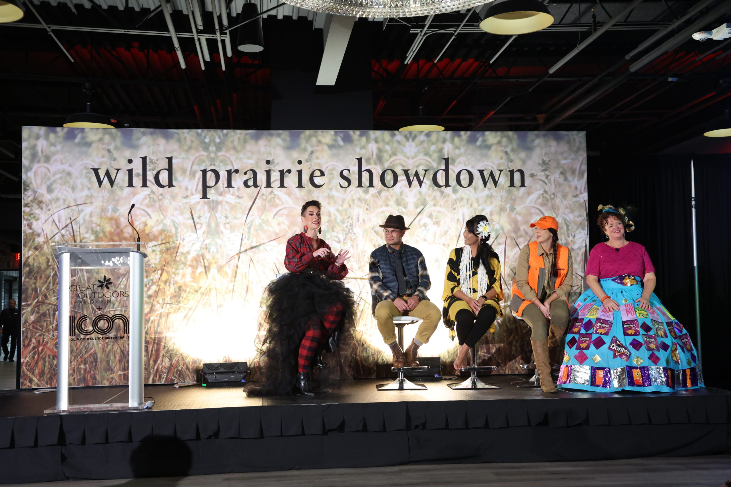 A group of people sitting on stage in wild outfits