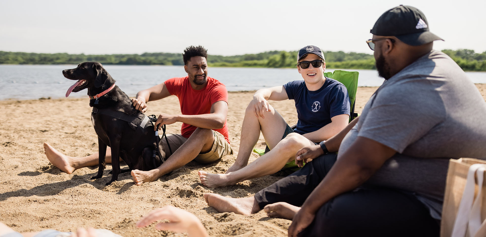 Three people chat while sitting on a beach