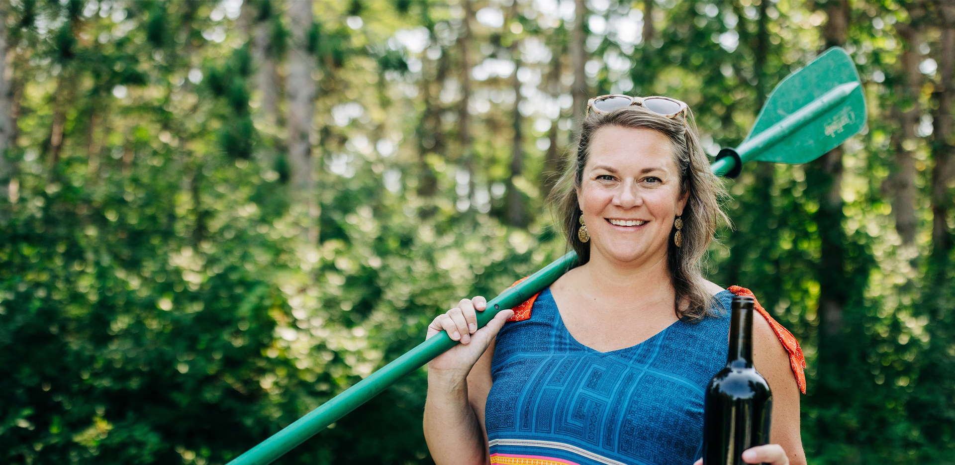 Joey Taylor Moon holding a dark glass bottle and a green oar