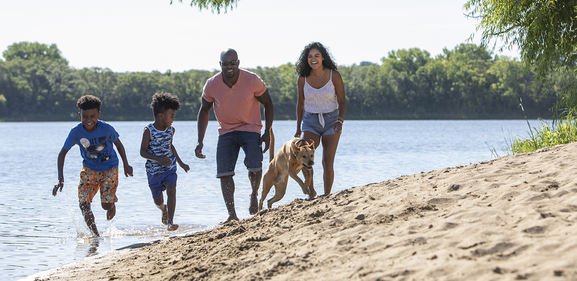 Family running down the beach with their dog