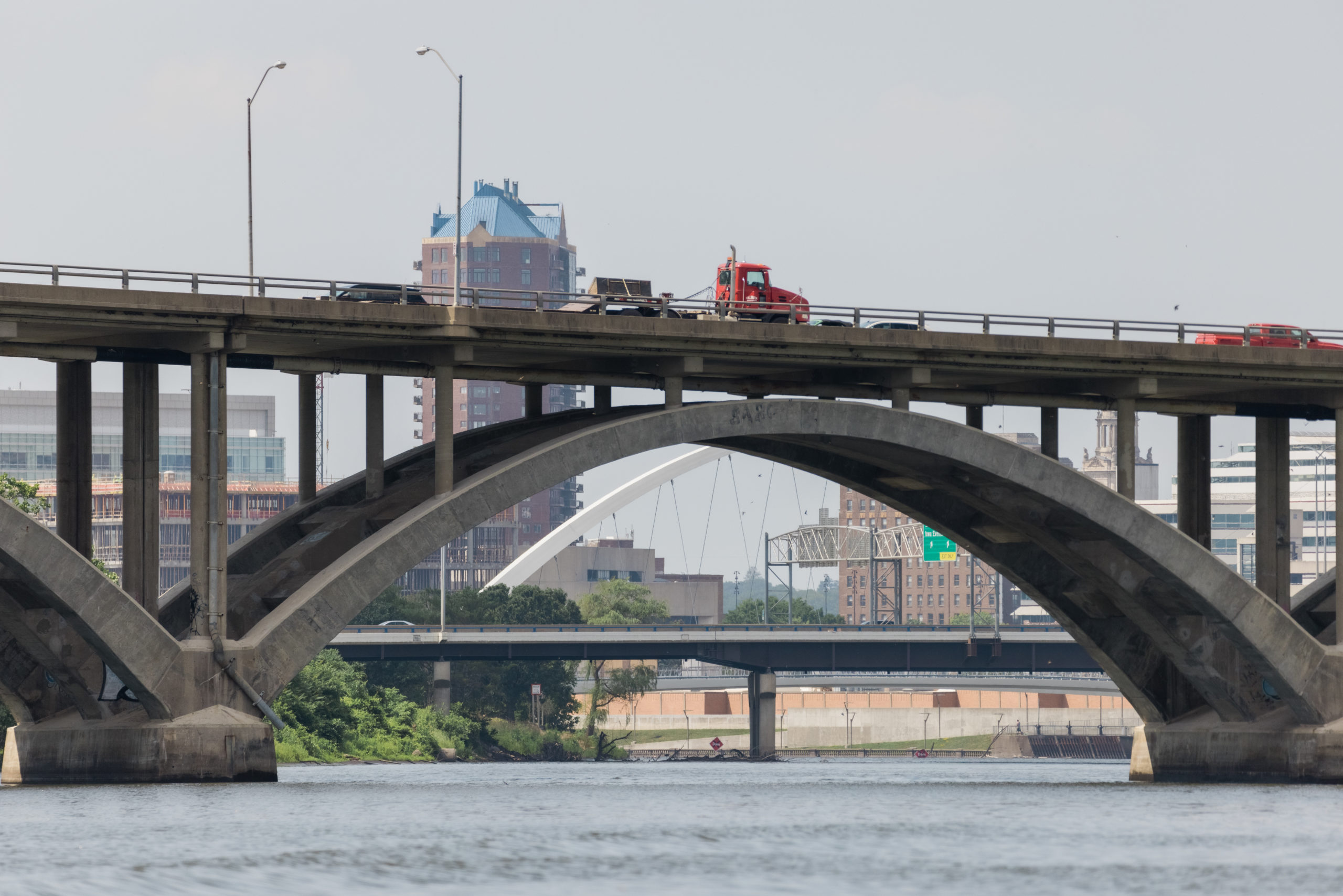A red semi truck passing over a bridge over the Des Moines River