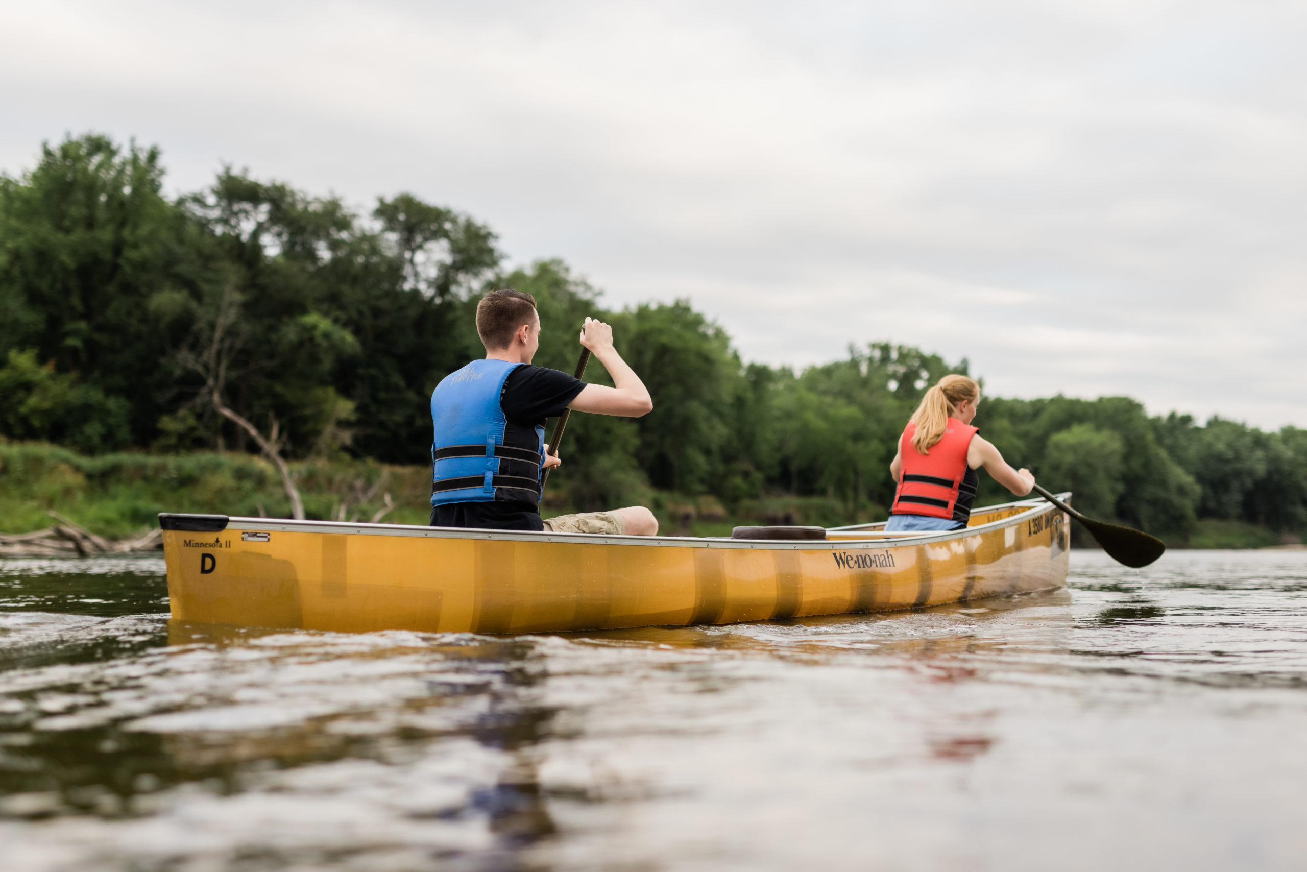 Two people padding a canoe down the river