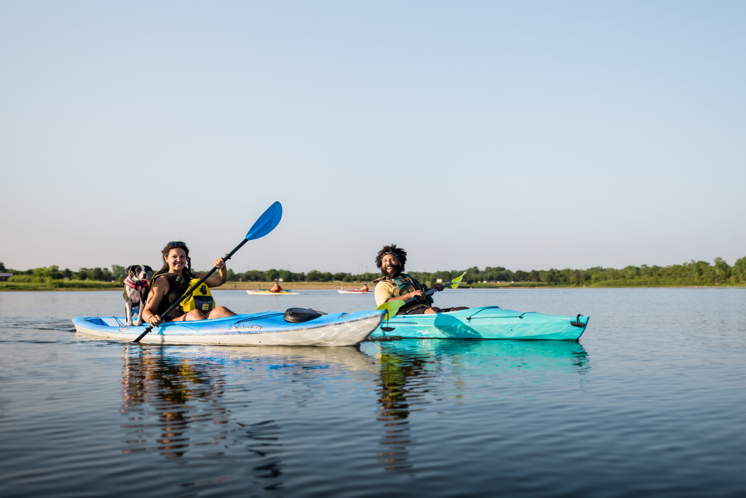 A couple paddling in kayaks with their dog