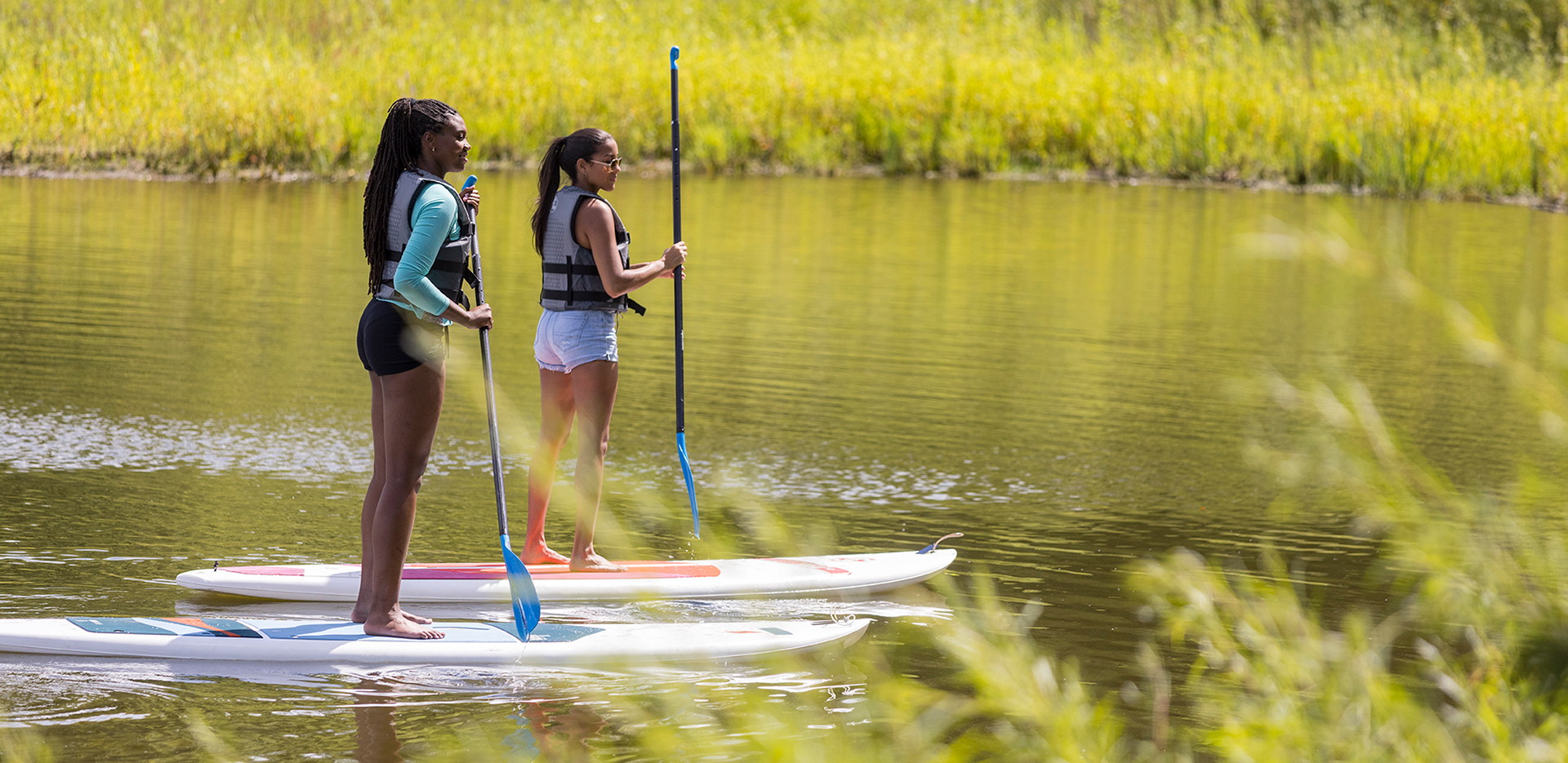 Two young women out on paddle boards on a body of water