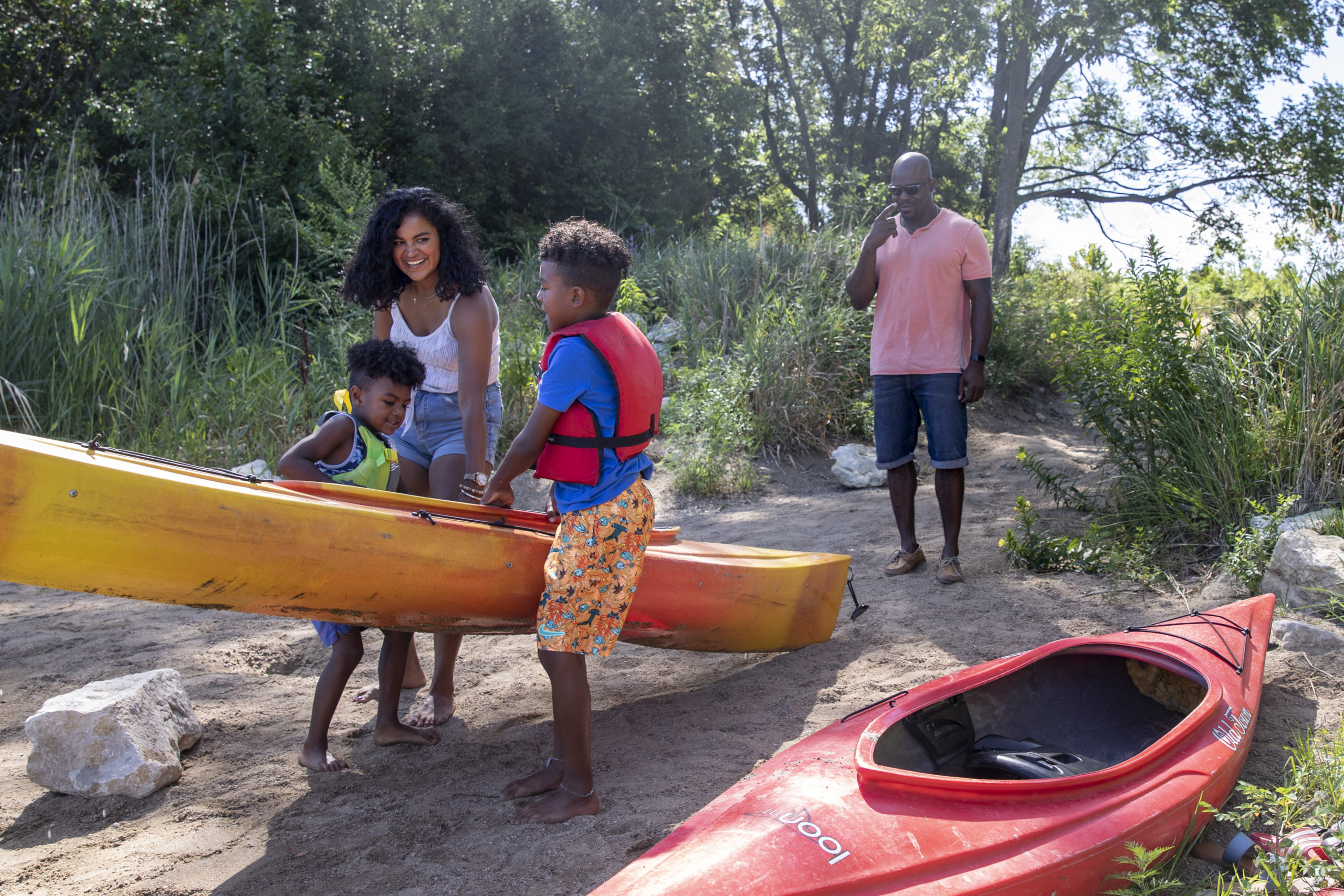 Kids helping their mom carry a kayak to the water